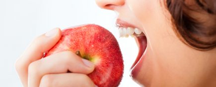 Healthy nutrition and healthy teeth or diet, young woman bites in a apple