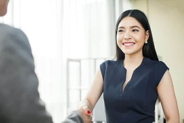 young woman shaking hands with business person