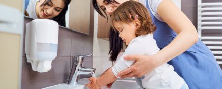 Kid washing hands with mom in the bathroom.