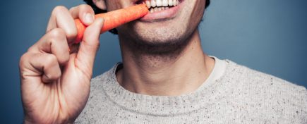 Young man eating a carrot