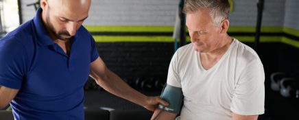 Personal trainer measuring mature man's blood pressure