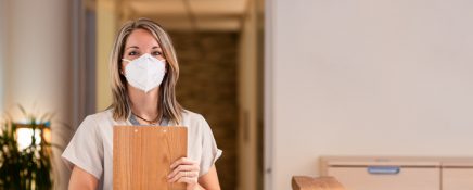 woman receptionist holding folder with documents and with mask in hospital