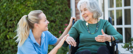 Smiling Personal Support Worker Talking with Old Woman in Wheelchair