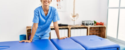 Female massage therapist stands near the massage table