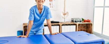 Female massage therapist stands near the massage table