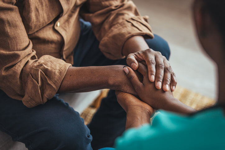A Community Service Worker provides emotional support by holding their client’s hand after Community Service Worker Training.