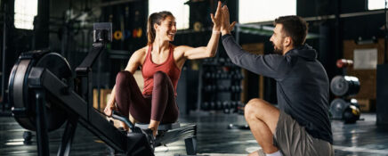 Man pursuing health and fitness training gives a high-five to a client