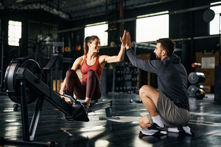 Man pursuing health and fitness training gives a high-five to a client