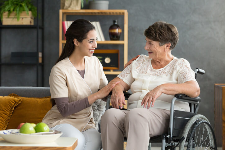 Female PSW assisting senior woman in a wheelchair after personal support worker training