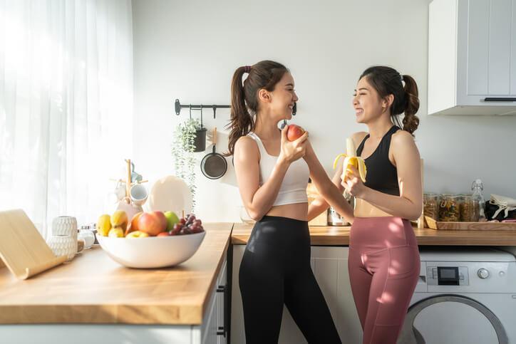 Two health and fitness graduates chatting and eating fruits after a workout