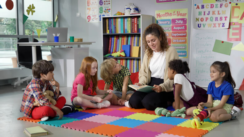 early childcare assistant reading a story to children