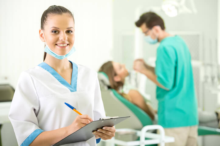 student holding a clipboard in dental assistant courses