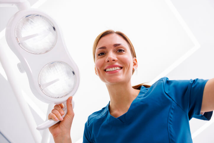 graduate holding a light after dental assistant courses