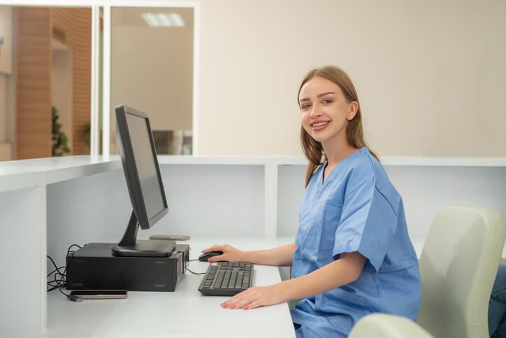 A woman working on the computer at her Medical Office Admin position.