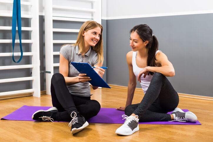 A female fitness instructor with a smiling female client after completing her health and fitness certificate program.