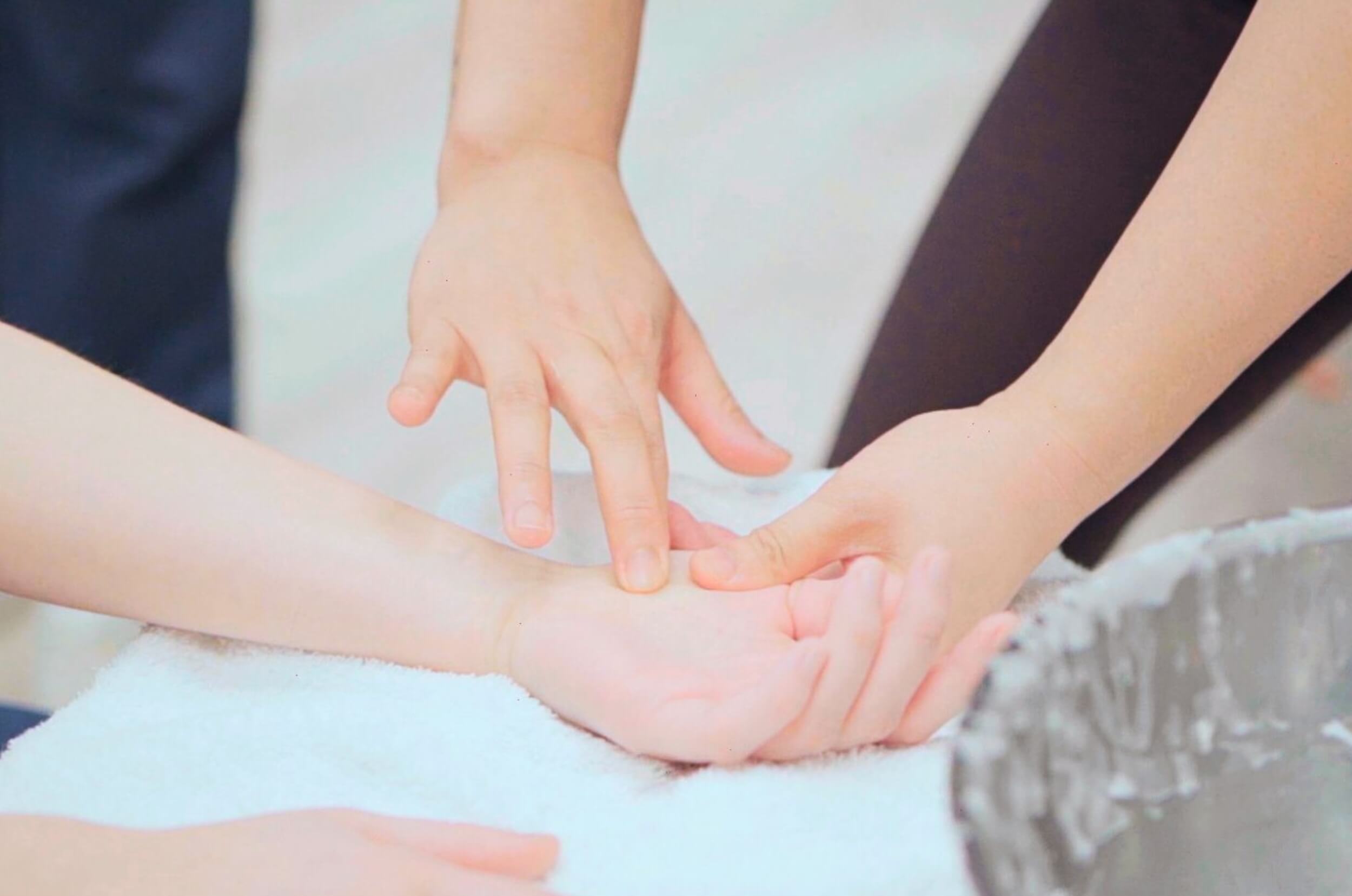 A student learning to massage a hand in one of her massage therapy courses classes.