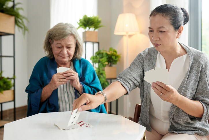 A PSW grad practicing GPA dementia care while playing cards with their client