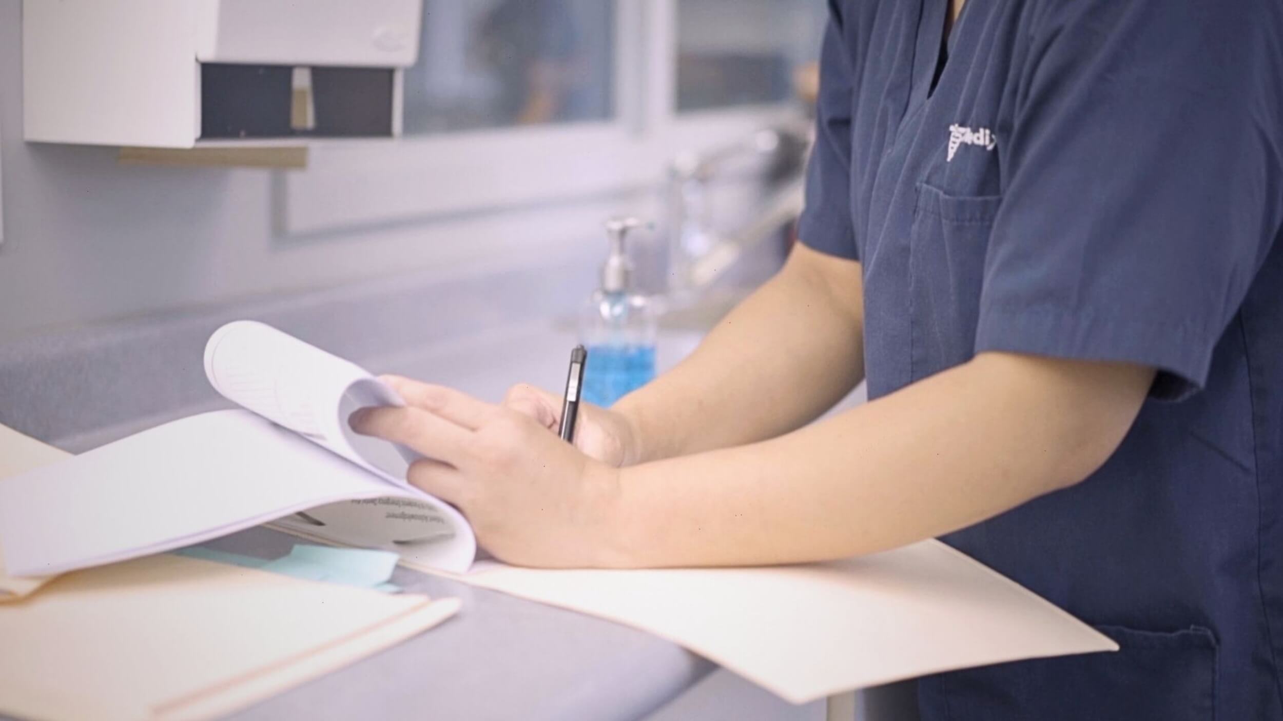 A male dental assistant writing in a notepad after his Dental Assistant Diploma.