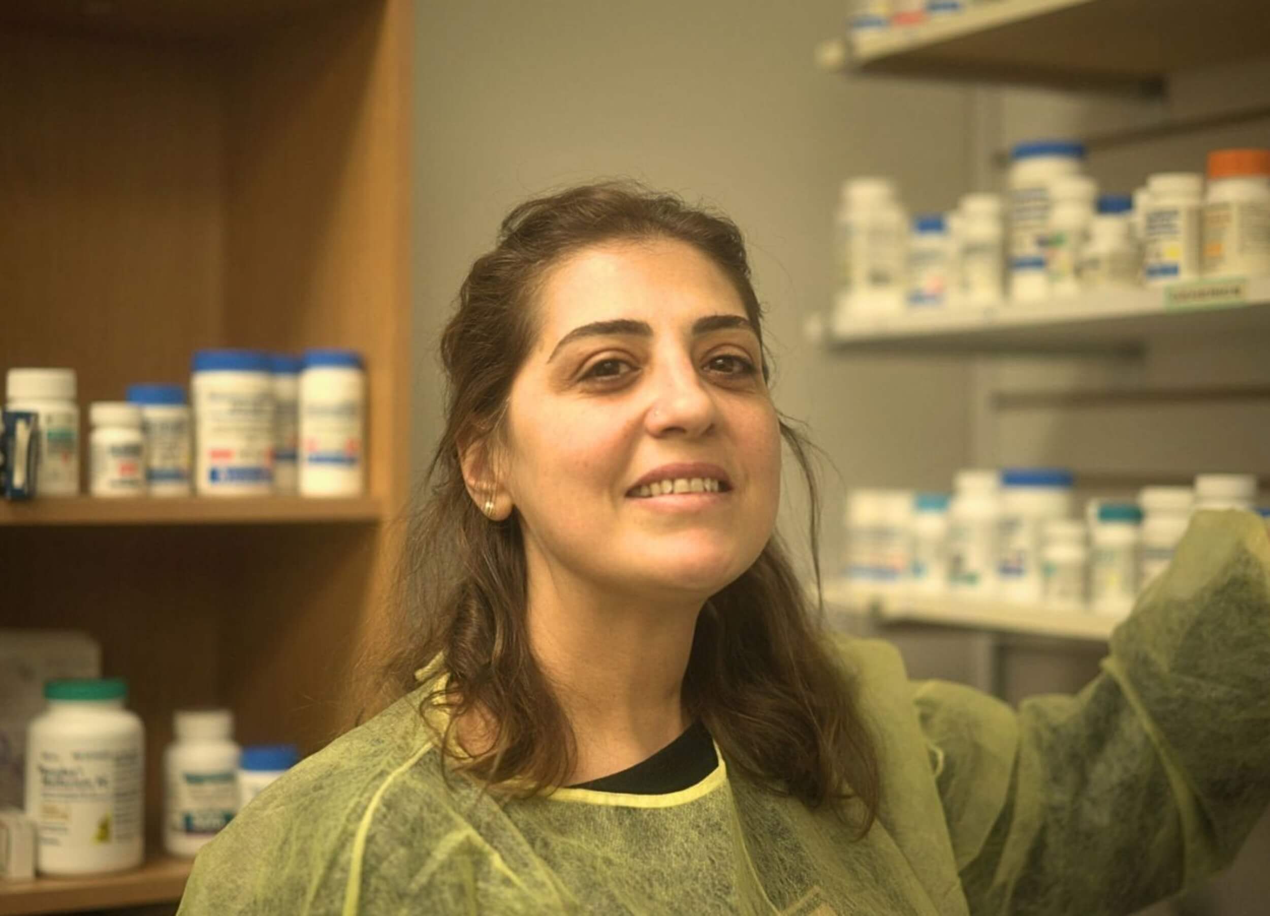 A Pharmacy Assistant course student posing in front of medications on shelves