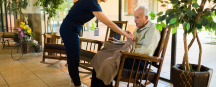 A personal support worker covering an elderly client with a blanket