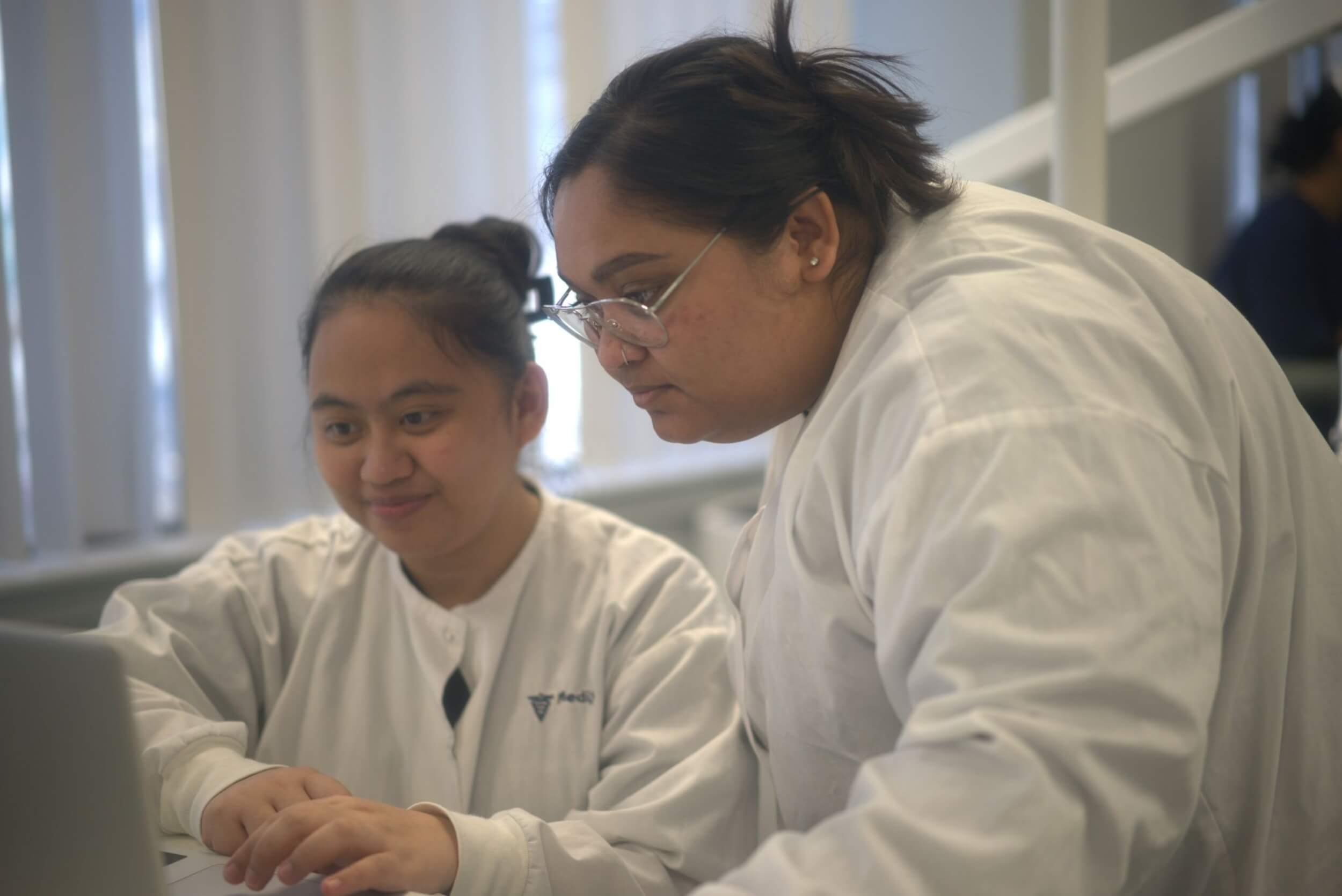 A pair of students completing a dental assistant program in Toronto working together on the computer