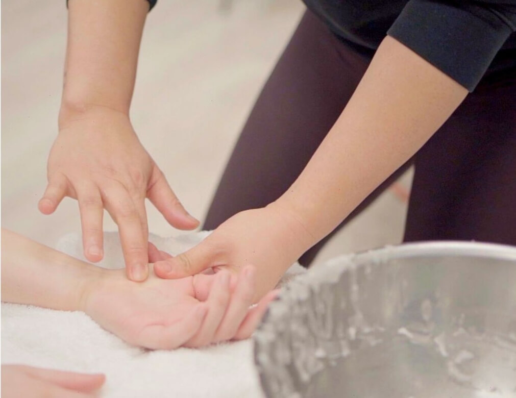 A massage therapist working on a client’s hand