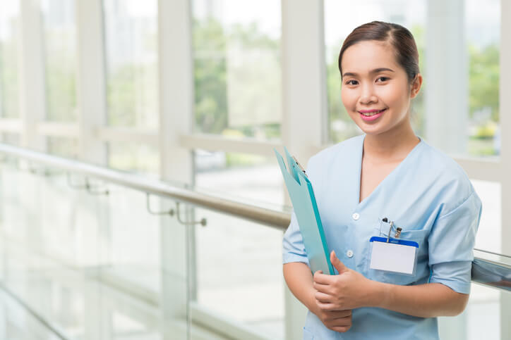 A medical office assistant online course grad posing in uniform at a clinic