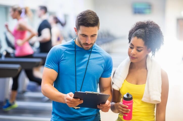 Woman next to personal fitness trainer at the gym