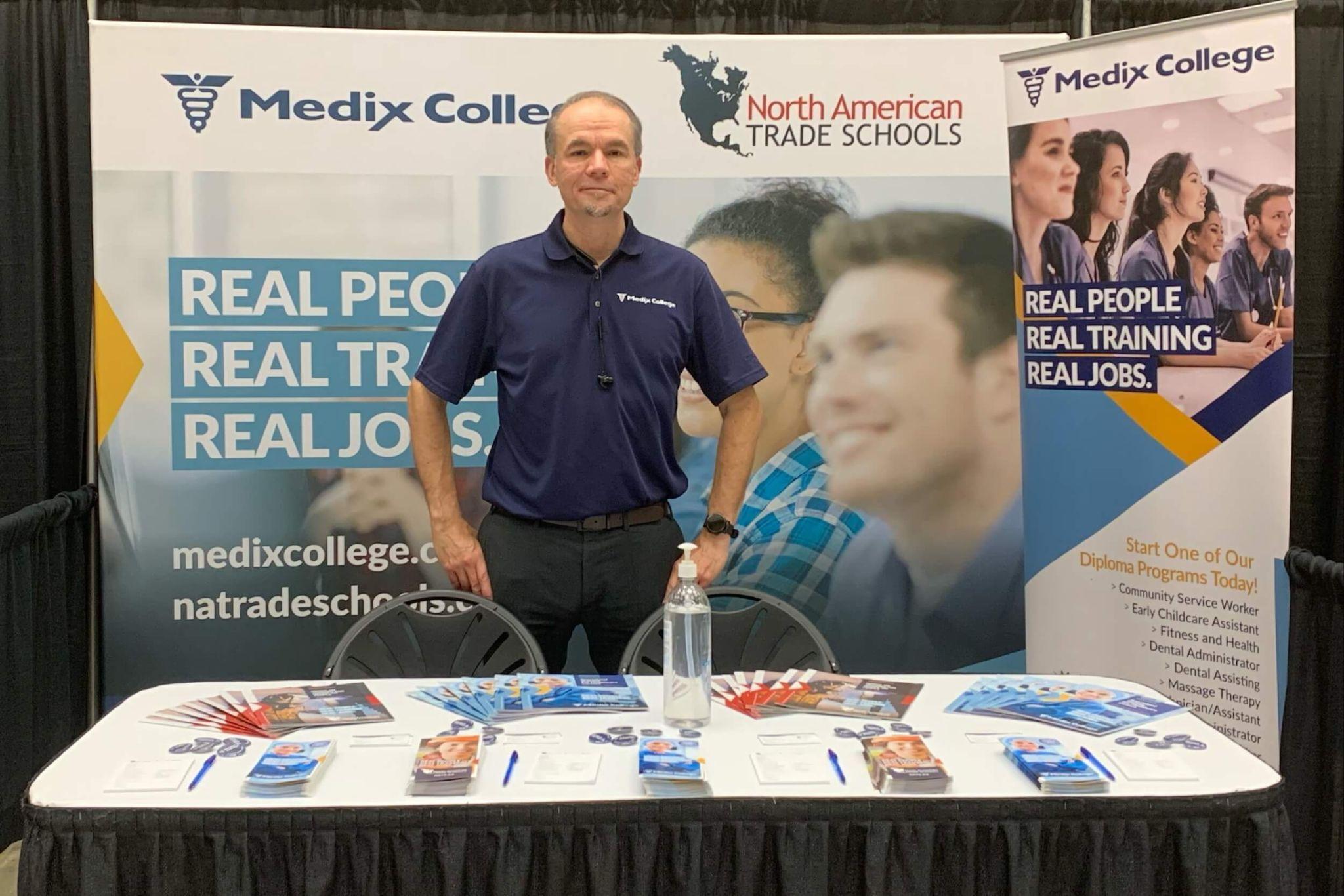 A Medix College representative at a booth showcasing the benefits of online vs. in-person classes.