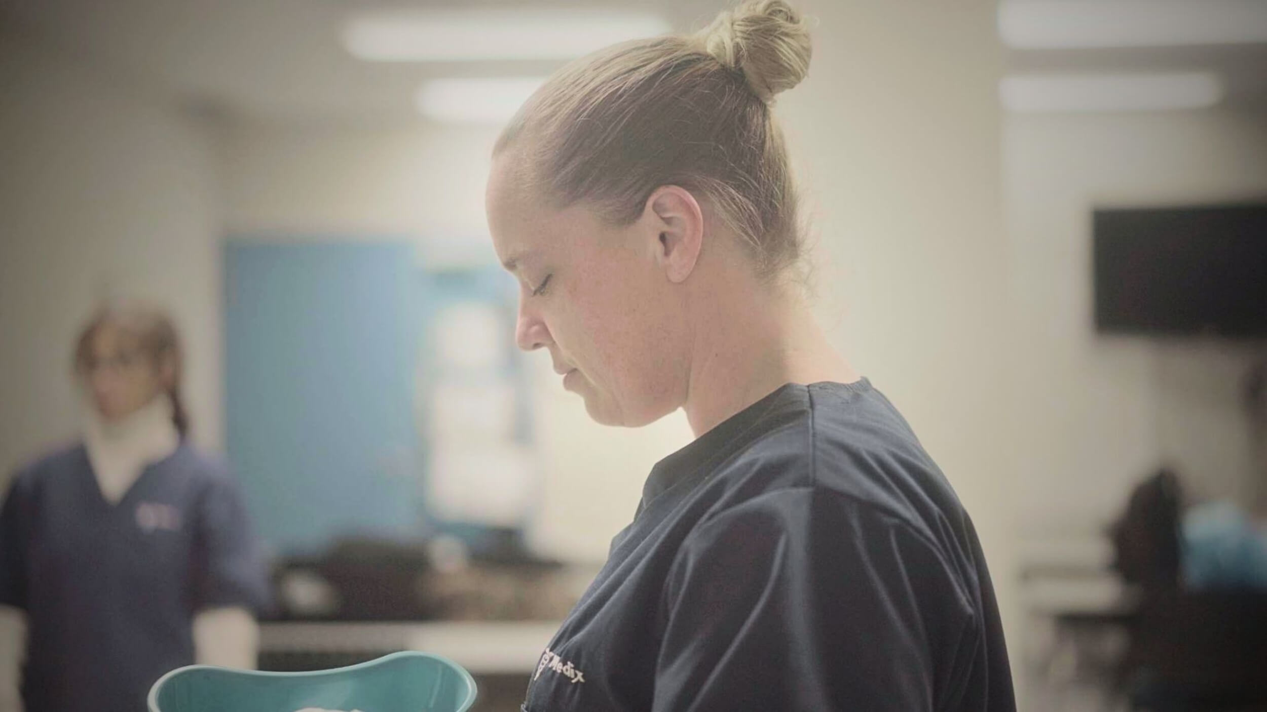 A PSW holding a medical tray in a hospital after completing a personal support worker online course