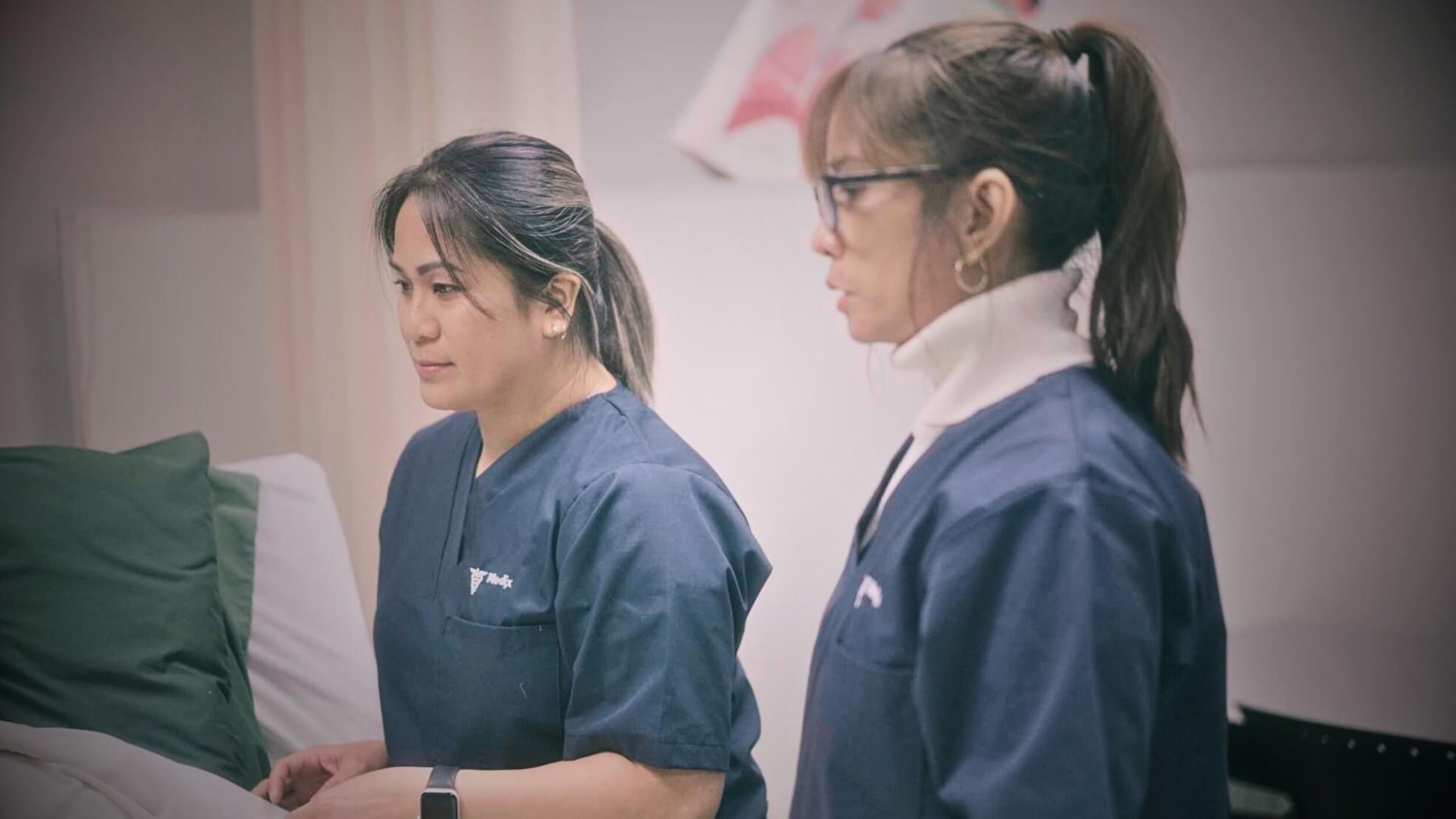 Two female PSWs dressing a patient’s bed after completing their personal support worker online course