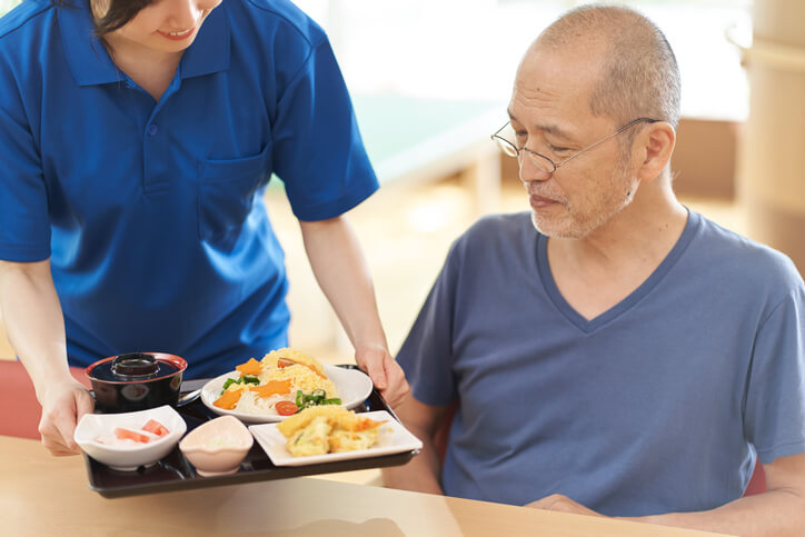 A food service worker training program grad serving food to a resident