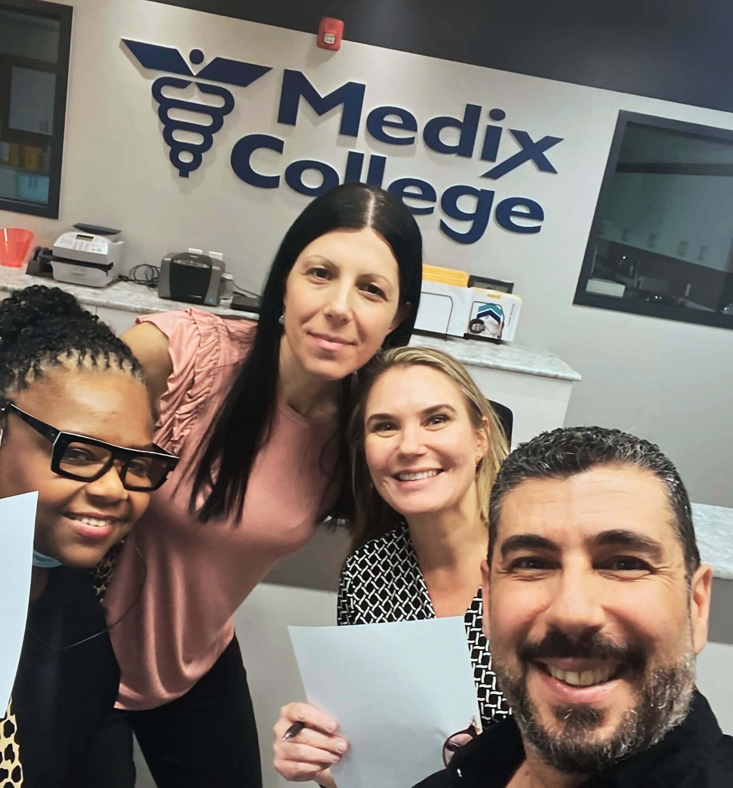 A trio of students in front of a Medix College sign during their healthcare courses in Canada