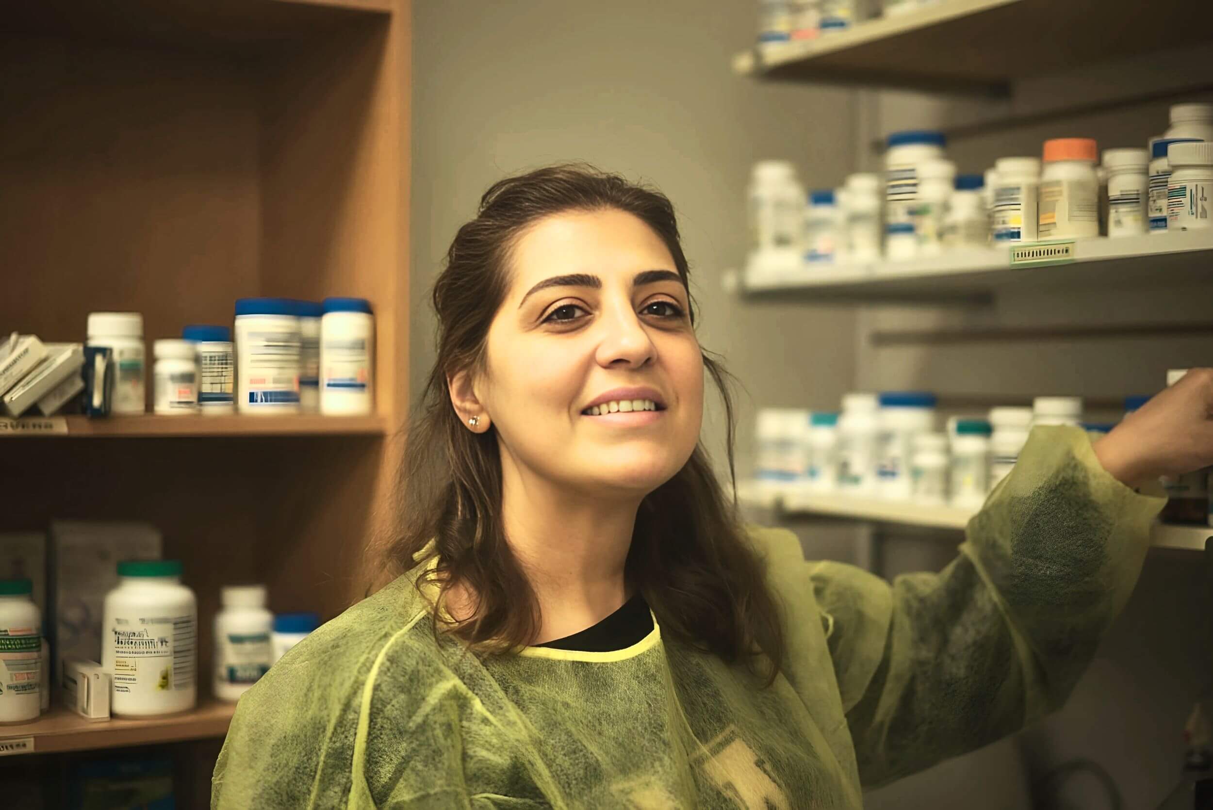 A student in the pharmacy assistant program in front of a shelf of medications