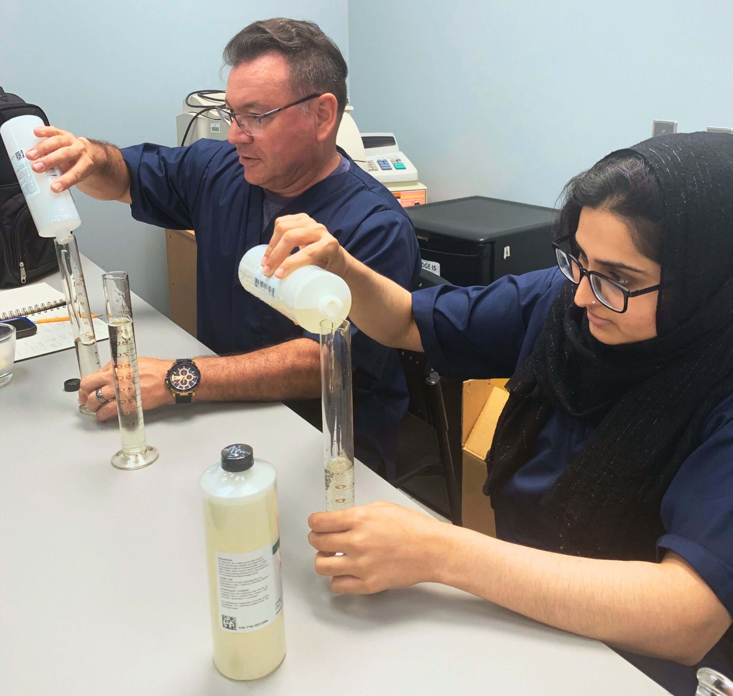 Two students at Medix Career College engage in hands-on training, carefully measuring liquids in a lab to develop essential scientific skills.