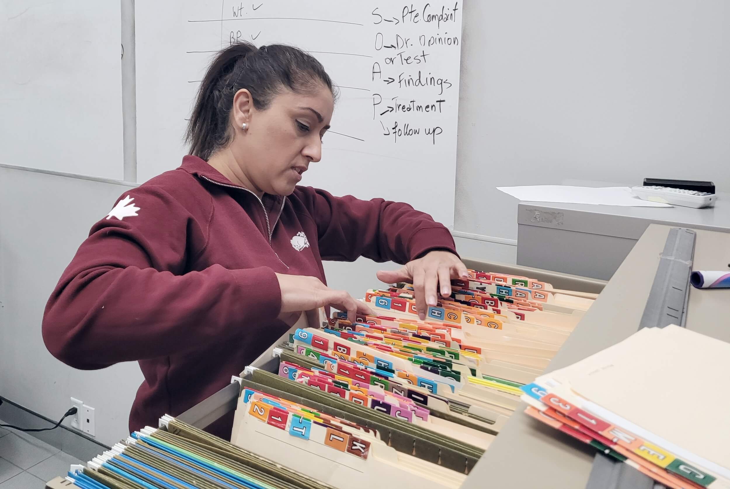 A focused healthcare college student organizing files in a classroom