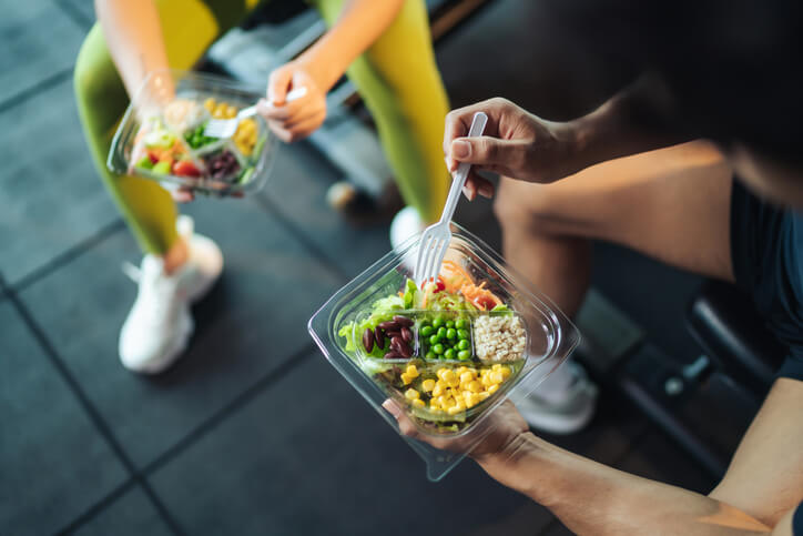 A health and fitness certificate holder looking at nutrition facts of yogurt container at a grocery store