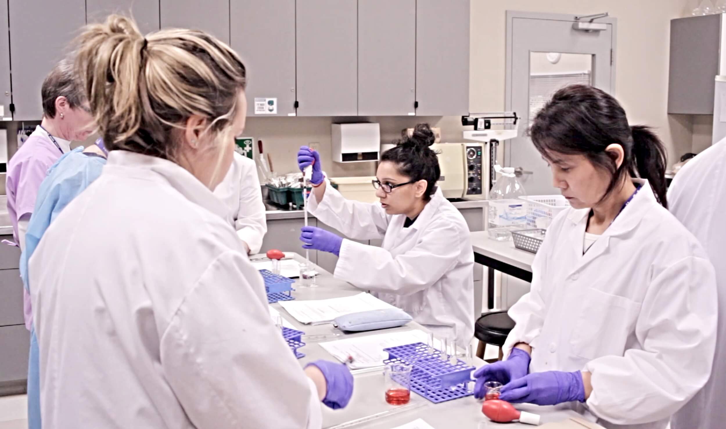 A group of medical lab assistant/technician program students practicing lab techniques in a classroom