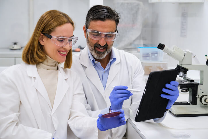 An Ontario healthcare worker in a lab coat supporting a medical laboratory technician